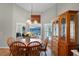 A well-lit dining area with a wooden table set and a hutch with windows looking to the outside at 27018 Nature View St, Leesburg, FL 34748