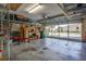 Spacious garage with ample storage shelving, workbench, and visible exterior through the open door at 27146 Greenfly Orchid Ln, Leesburg, FL 34748