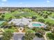 Aerial view of community clubhouse with pool, manicured lawns and landscaping, with golf course and residential homes beyond at 3074 Eastwood Ter, The Villages, FL 32163