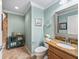 Charming bathroom with granite counters, decorative teal cabinet, framed mirror, and neutral tile flooring at 3074 Eastwood Ter, The Villages, FL 32163