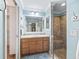 Well-lit bathroom with a large vanity, a framed mirror, and a walk-in shower with tiled walls at 3074 Eastwood Ter, The Villages, FL 32163
