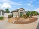 Lush landscaping adorns this home's front yard, featuring vibrant plants, mulch, and a curved retaining wall at 3074 Eastwood Ter, The Villages, FL 32163