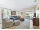 Bright living room features tile flooring, a comfortable blue sofa, and sliding glass doors to the outside patio at 3074 Eastwood Ter, The Villages, FL 32163