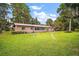 Expansive backyard featuring a lush lawn, mature trees, and a brick home exterior at 31941 Tropical Shores Dr, Tavares, FL 32778