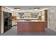 Kitchen boasts wood cabinets, an island cooktop, and a black refrigerator, with natural light from a window at 31941 Tropical Shores Dr, Tavares, FL 32778
