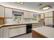 Bright kitchen with white cabinetry, black dishwasher, tile floors, and two windows above the countertop at 31941 Tropical Shores Dr, Tavares, FL 32778