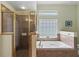 Bathroom features a shower with glass door, a soaking tub with tile surround, and a window for natural light at 3257 Baltic Sea Blvd, Tavares, FL 32778