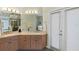 Bright bathroom with double sinks, wood cabinets, and a large mirror with decorative lighting at 3257 Baltic Sea Blvd, Tavares, FL 32778