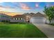 Home at sunset featuring a green lawn, manicured hedges, and a two-car garage at 3257 Baltic Sea Blvd, Tavares, FL 32778
