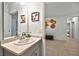 Well-lit bathroom featuring a modern sink, decorative cow art, and neutral-toned tiles extending into the hallway at 33960 Sky Blossom Cir, Leesburg, FL 34788
