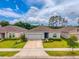 Charming single-story home with a well-manicured lawn, complemented by a paved driveway and lush greenery at 33960 Sky Blossom Cir, Leesburg, FL 34788