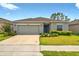 Charming single-story home with a well-manicured lawn, a two-car garage, and beautiful landscaping at 33960 Sky Blossom Cir, Leesburg, FL 34788