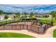 Community playground featuring swings, slides, and climbing structure surrounded by a black metal fence and lush landscaping at 33960 Sky Blossom Cir, Leesburg, FL 34788