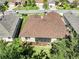 Aerial view of a well-maintained home with a brown roof, surrounded by lush trees and manicured lawns in a quiet neighborhood at 3519 Arlington Ridge Blvd, Leesburg, FL 34748