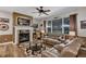 Open living room with a large leather couch, fire place, cow-hide rug, and a ceiling fan at 3519 Arlington Ridge Blvd, Leesburg, FL 34748
