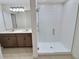 Bathroom showcasing glass shower, double sinks with quartz countertop and wood cabinetry at 358 Switchgrass Loop, Minneola, FL 34715
