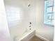 Bathroom with a tiled shower and tub combination next to a window with blinds at 358 Switchgrass Loop, Minneola, FL 34715