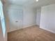 Bedroom with neutral carpet, white walls, a window, and double door closet at 358 Switchgrass Loop, Minneola, FL 34715