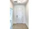 Bright entryway with a modern white door and neutral tiled flooring at 358 Switchgrass Loop, Minneola, FL 34715