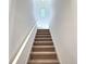Clean carpeted staircase with white walls and handrail leading to the upper level of the home at 358 Switchgrass Loop, Minneola, FL 34715