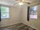 Neutral bedroom with wood laminate floors, ceiling fan, and two windows at 365 Fletcher Ave, Daytona Beach, FL 32114
