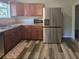 Well-equipped kitchen with stainless steel refrigerator, wood cabinets, and modern flooring at 365 Fletcher Ave, Daytona Beach, FL 32114