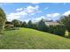 Well-maintained backyard featuring a lush green lawn, manicured hedges, and a beautiful, partly cloudy sky at 39504 Hillrise Ln, Lady Lake, FL 32159