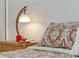 Close-up of a bed featuring patterned bedding with a wooden nightstand with lamp at 40140 Palm St, Lady Lake, FL 32159