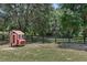 Quaint red chicken coop with chickens in the fenced yard with large trees at 40143 Babb Rd, Umatilla, FL 32784