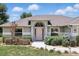 Welcoming front exterior with manicured garden, and soft pink front door and sidelight windows at 40143 Babb Rd, Umatilla, FL 32784