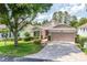 Front exterior of a well-maintained home with a paver driveway, mature tree, and manicured landscaping at 4083 Capland Ave, Clermont, FL 34711