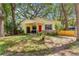 Quaint home featuring a cozy front porch and a vibrant red door, surrounded by lush greenery at 43 Almond Pass Dr, Ocala, FL 34472