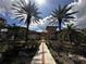 Beautiful clubhouse exterior showcasing palm trees, landscaping, and tiled roof under blue skies with sunshine at 5560 Metrowest Blvd # 3-204, Orlando, FL 32811