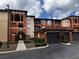 Multi-story condo building with red brick and light beige exterior, attached garages, and lush landscaping at 5560 Metrowest Blvd # 3-204, Orlando, FL 32811