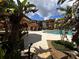 A view of the community pool featuring palm trees and tropical foliage under a partly cloudy sky at 5560 Metrowest Blvd # 3-204, Orlando, FL 32811
