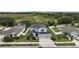 Aerial view of a gray two-story home with a three car garage and fenced yard located in a lush community at 605 Black Eagle Dr, Groveland, FL 34736