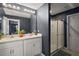 Bathroom with double sinks, large mirror with lighting, and enclosed walk-in shower with glass doors at 605 Black Eagle Dr, Groveland, FL 34736
