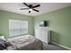 A cozy bedroom with green walls, white dresser, ceiling fan, and lots of natural light at 605 Black Eagle Dr, Groveland, FL 34736