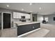 Well-lit kitchen with stainless steel appliances, white cabinets, and an island with sink, with open access to living room at 605 Black Eagle Dr, Groveland, FL 34736