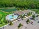 Community clubhouse featuring a pool and ample parking, surrounded by lush greenery and a serene lake at 6301 Whittle Ct, The Villages, FL 32163