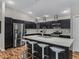 Modern kitchen features stainless steel appliances, dark cabinets, island with barstool seating, and wood floor at 6301 Whittle Ct, The Villages, FL 32163