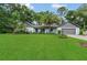 Charming single-story home boasts a lush green lawn and mature landscaping with palm trees at 717 Southeast 46Th Ct, Ocala, FL 34471