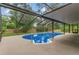 Backyard pool area enclosed with a screened cage and view of the surrounding trees at 717 Southeast 46Th Ct, Ocala, FL 34471