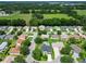 Neighborhood aerial view, highlighting homes with green lawns, mature trees, and a golf course in the distance at 750 Eden Pl, The Villages, FL 32162