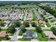 Expansive aerial view showcasing a residential neighborhood with well-maintained homes and verdant landscaping, adjacent to open green space at 750 Eden Pl, The Villages, FL 32162