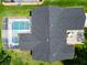 Aerial view of a home with a screened-in pool, patio area, and dark shingled roof surrounded by lush landscaping at 750 Eden Pl, The Villages, FL 32162