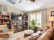 Cozy living room featuring a leather sofa, bookshelves, a TV, and a window with natural light at 750 Eden Pl, The Villages, FL 32162