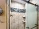 Shower with a sliding glass door and decorative tile inset at 750 Eden Pl, The Villages, FL 32162