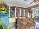 Patio tiki bar with tiki decorations, bar stools, and lush landscaping at 750 Eden Pl, The Villages, FL 32162