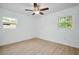 Spacious bedroom with neutral walls, light wood floors, a ceiling fan, and natural light from two windows at 841 S Michigan Ave, Groveland, FL 34736